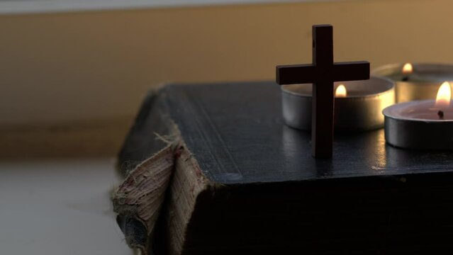 Holy bible with crucifix and tea light candles 