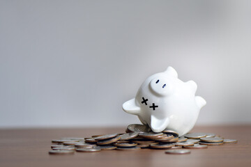 The dead piggy bank lies upside down on coins, Economic crisis, Decrease, layoff, job fired, pay cuts, low cost, collection - obrazy, fototapety, plakaty