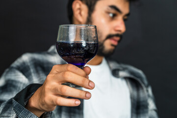 Discover the perfect blend of elegance and confidence in this captivating display of a young man with his wine drink