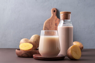Concept of alternative milk. Glass with potato milk on brown background.