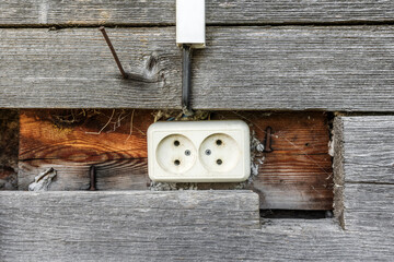 An old electrical outlet on the wooden wall of a village shed 