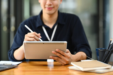 Smiling male office worker using stylus pen writing on digital tablet. Business, technology and...