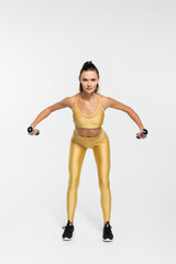 fit sportswoman in fitness clothes training with dumbbells on white background, fitness motivation