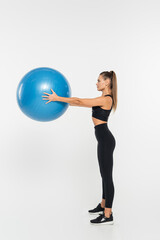 fit sportswoman holding fitness ball while exercising on white background, athletic woman concept