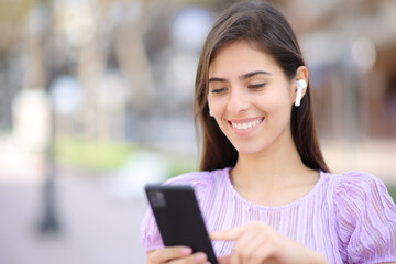 Happy woman with earphone and phone walking