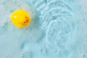Yellow rubber duck floating on blue water