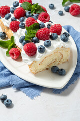 Sponge biscuit cake roll filling whipped cream and berries decorated raspberry, blueberry