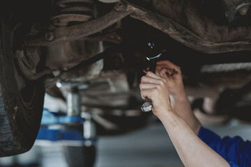 Professional mechanic checking and repairing a car. Auto mechanic working in garage. Repair service.