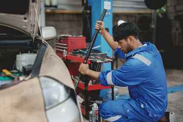 Fototapeta na wymiar Asian auto mechanic changing tires. Asia Man picks up a car jack to change a tire.