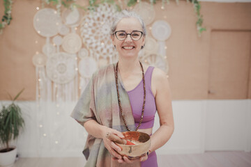 Hippie mature woman smiling while holding a Tibetan singing bowl