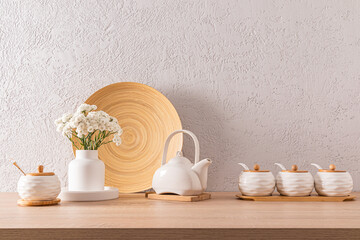 Fototapeta na wymiar Beautiful kitchen background of an eco-friendly kitchen. Front view of ceramic white storage jars, teapot, flower vase. gray cement wall.