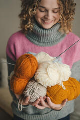 Beautiful curly-haired girl bears many color hanks of a yarn for knitting. Handmade concept. Relaxing hobby time.