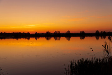 beautiful orange-yellow sunset on the lake in spring