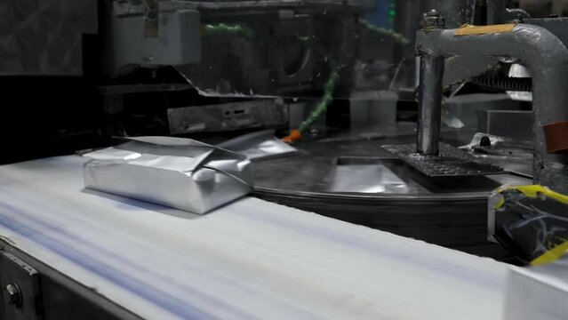Automated line for production of dairy food products in modern factory. Process automatic robots pack briquettes of butter cottage cheese ice cream in packaging on equipment line.