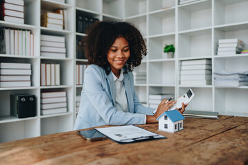 Real estate agent, African American businesswoman Africans use smartphone and calculators to offer mortgages to their clients. Home mortgage and insurance finance concepts.