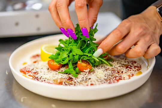 woman chef hands cooking carpaccio with arugula and cheese on kitchen