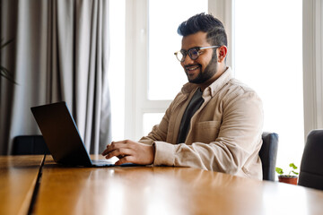 Smiling business man working on laptop while sitting in office