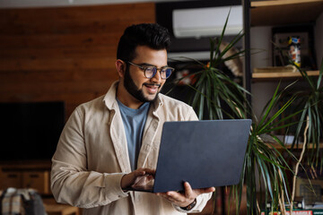 Smiling business man working on laptop while standing in office - 626855679