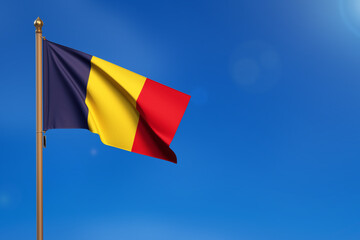 Romania. Flag blown by the wind with blue sky in the background.