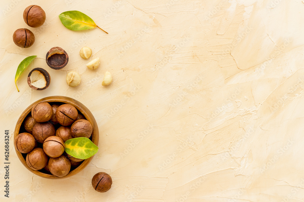 Wall mural shelled macadamia nuts in bowl with green leaves. protein food