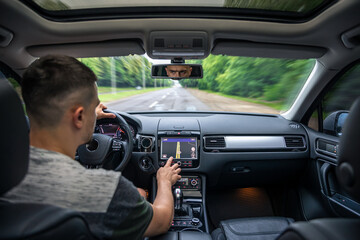 Man touching screen of a GPS navigation system in his car.