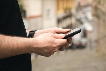 Smartphone in the hands of a man close-up on a blurred background, the concept of using technology, shopping online, communicating remotely.