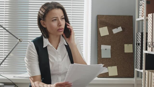 Medium slowmo of young Biracial female security service manager having phone conversation while working with male colleague in modern officeMedium slowmo of young Biracial female security service mana