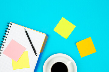 Notepad, cup of coffee and paper reminders on a blue background.