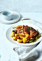 Mediterranean-style chicken with lemon, garlic, olives and herbs and baked potatoes. Oven baked chicken legs
