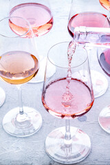 Rose wine pour into a glass at a tasting. Pink wines, drinks on a table at a winery. An assortment of wines of many different colors