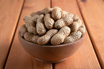 Bowl full of shelled peanuts on wooden background,closeup

