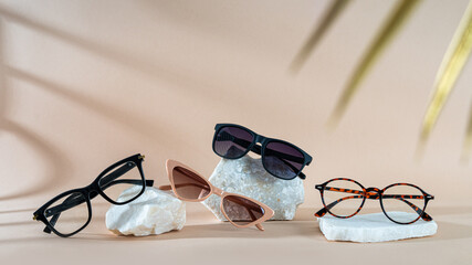 Set of different sunglasses and eyeglasses on stones on a beige background. Summer fashion eyeglasses collection. Sunglasses sale, discount, promotion banner. Minimal style flat lay, copy space