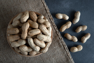 Bowl full of shelled peanuts on dark background,top view