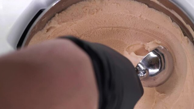 Seller scooping tasty ice cream from container, closeup