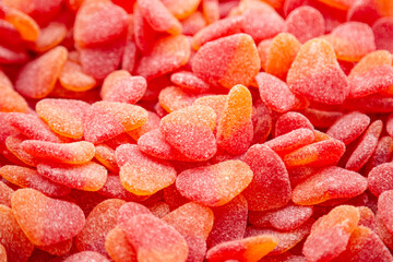 Background of red gummies in the form of hearts with a sugar coating.