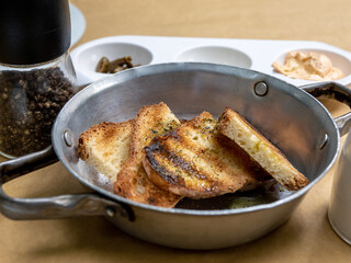 A slice of toasted bread in a bowl with sauces in the background