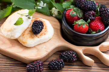 Morning breakfast with cheesecakes and strawberries and blackberries. Cooked breakfast is dietary and healthy