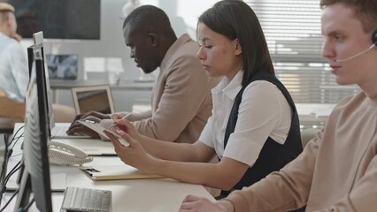 Waist up slowmo of team of young professional diverse security service specialists sitting by desktop computers in office monitoring data from CCTV cameras - Powered by Adobe