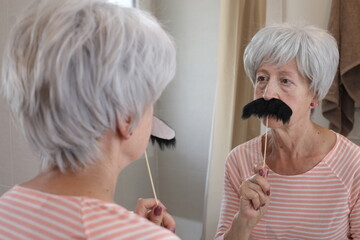 Senior woman pretending to have a vintage mustache  - obrazy, fototapety, plakaty