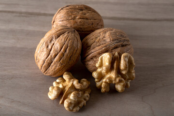 Peeled walnuts and whole walnuts in wooden table
