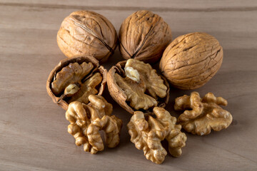 Peeled walnuts and whole walnuts in wooden table
