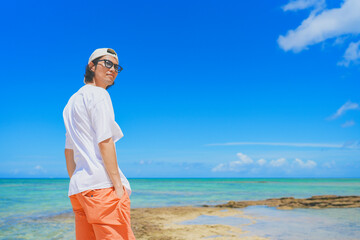 南国の美しいビーチを歩くサングラスをかけた男性