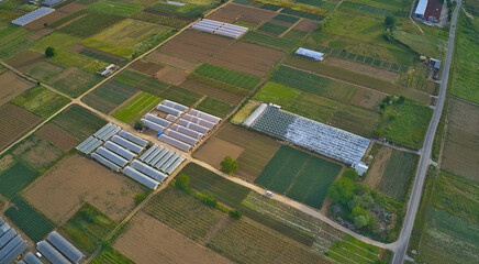 Farmland with greenhouses and various green fields. aerial view
