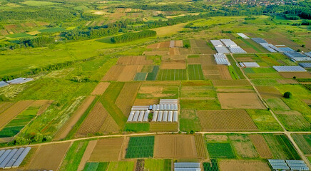 Farmland with greenhouses and various green fields. aerial view