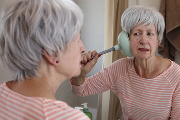Senior woman using a plunger to clean her earwax 
