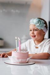Adorable three year old kid celebrating his birthday and blowing candles on homemade baked cake, indoor.