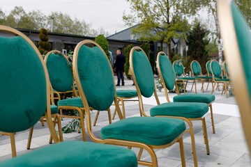 Wedding decor. Ceremony area with emerald chairs with gold legs, side view.