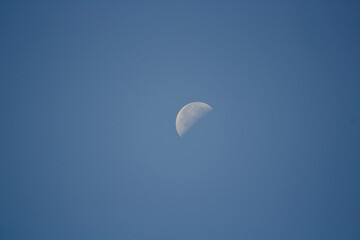 Moonscape. Moon in the sky during the day. White moon and blue sky.