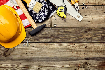 Happy Labor day concept. Construction tools, safety helmet, American flag on wooden table. Top view, flat lay.