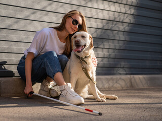 A blind woman walks her guide dog on the street. Girl hugging a labrador. 
